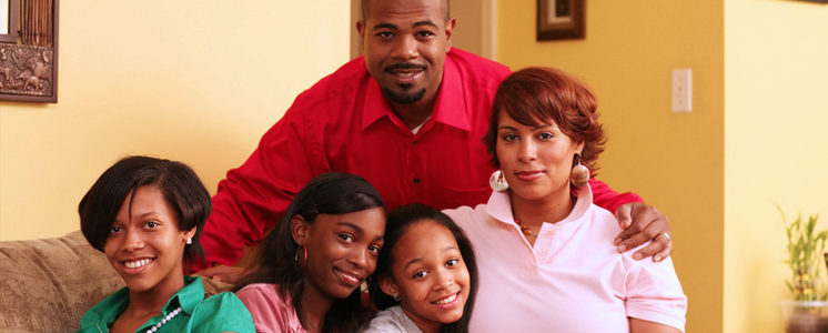A family poses together on a couch in a living room